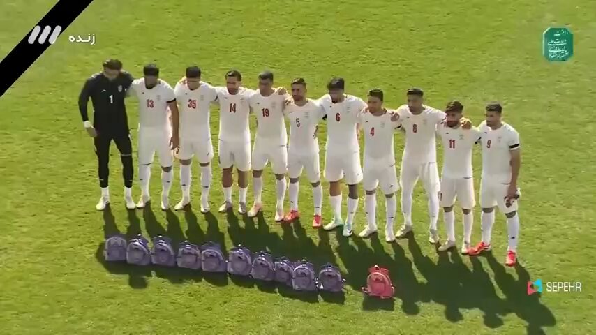 Los futbolistas iraníes colocaron pequeñas mochilas escolares de colores rosa y morado frente a ellos durante el himno